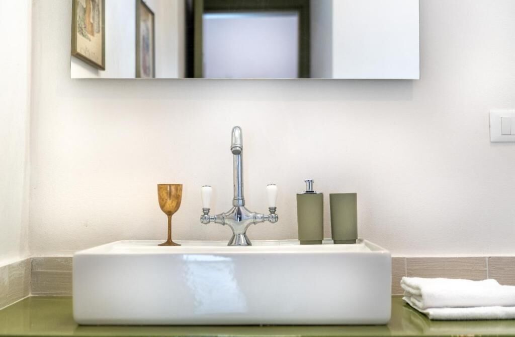A bathroom with a white sink, a mirror above it, and two bottles of soap on the counter.
