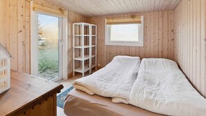 A wooden room with a bed, a window, and a door leading outside. - 4 Star Holiday Home in Humble (Sydlangeland)