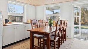A kitchen with a wooden table and chairs, white cabinets, and large windows. - 4 Star Holiday Home in Humble (Sydlangeland)