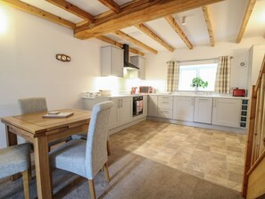 A kitchen with wooden beams, a dining table with chairs, and a window with curtains. - Ascot, Overton near Ellesmere. (Wrexham)