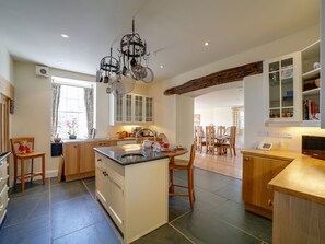 A spacious kitchen with a central island, wooden cabinetry, and a chandelier. - Porthcothan House, Porthcothan (Padstow)