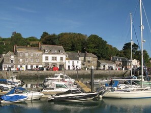 A harbor with boats docked, a building with multiple windows, and a stone wall. - Porthcothan House, Porthcothan (Padstow)