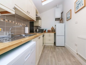 A compact kitchen with a dishwasher, a sink, a stove, and a refrigerator.