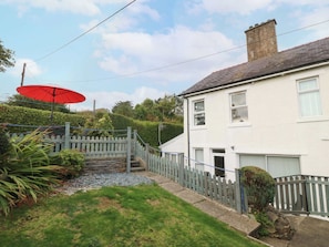 A residential property with a white exterior, a grey fence, a red umbrella, and a stone pathway leading to the entrance.
