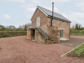 A stone house with a balcony, a chimney, and a gravel driveway.