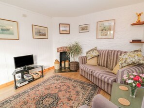 A living room with a sofa, a television, a patterned rug, and framed pictures on the wall.