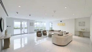 Un salon spacieux avec un grand canapé, une table basse et une table à manger. Une grande fenêtre offre une vue sur l’extérieur.