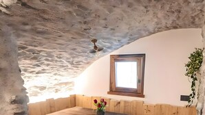 A rustic interior with a wooden bench seating area, a small window, and a plant on the wall. - Giuly's Home Luxury Bormio – Alpine Comfort and Wellness (Bormio)