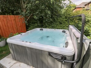 Ein Whirlpool mit Holzaußenverkleidung, Metallrahmen und einem Schlauchanschluss.