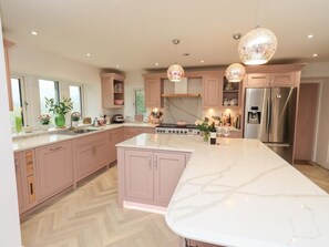 Una cocina moderna con una isla grande, electrodomésticos de acero inoxidable y armarios color rosa.