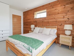 Ein Schlafzimmer mit Holzwandverkleidung, einem Bett mit weißer Bettwäsche, zwei Nachttischlampen und einem kleinen Nachttisch.
