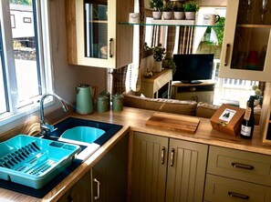 Une cuisine équipée d’un évier, de placards, d’une télévision et d’une fenêtre.