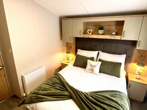 Une chambre à coucher avec un lit, des tables de chevet, un radiateur et une étagère au-dessus du lit.