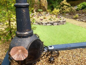 Un jardin avec un chemin en pierre, un barbecue en métal et une petite pelouse.