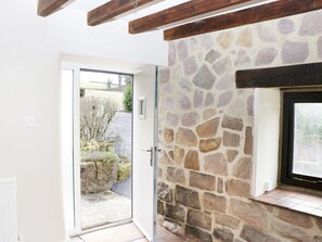 A room with a stone wall, a door leading outside, and a window with a view of the outdoors. - Woodlands Farm: Countryside Oasis (Ashbourne)