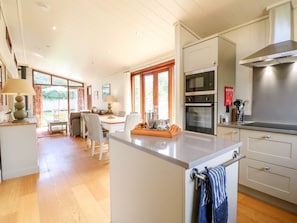 A modern kitchen with a central island, built-in ovens, and a dining area with a view. - TICKENCOTE, stylish interior, WiFi, Exton (Oakham)