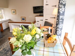 A dining table with a floral centerpiece, a bottle, and a basket with bread. - Hobson's Cottage - Pet-Friendly Retreat (Richmond)