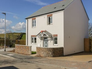 A two-story house with a stone foundation, a grey roof, and a front porch. - 4 Trerammet Crescent, Tintagel (Tintagel)