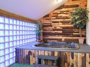 Ein Wellnessbereich mit Holzwand, Whirlpool und Pflanzen in Töpfen.