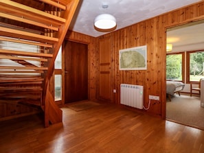 A wooden interior with a staircase, a radiator, and a window with a view. - Ringstead Lodge Heacham 4-bed (King's Lynn)