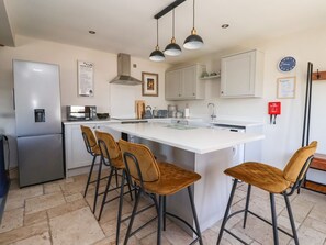 Eine moderne Küche mit Kochinsel, Barhocker und Kühlschrank.