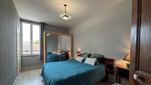 Ein Schlafzimmer mit Bett, Nachttischen, einem Spiegel und einem Fenster.