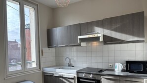 Eine Küche mit Fenster, Spüle, Herd, Mikrowelle und Wasserkocher.