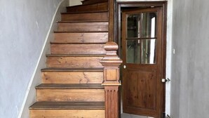Eine Holztreppe führt zu einer Tür mit einem Schachbrettmuster auf dem Boden.