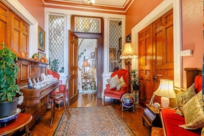 A traditional room with a wooden piano, red armchairs, a globe, and a patterned rug. - Charming Flat 8 in Lynmouth (Lynmouth)
