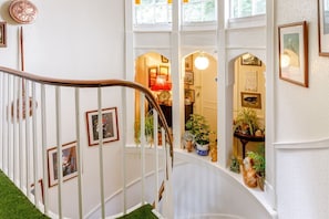 A staircase with white railings, framed pictures, and potted plants. - Charming Flat 8 in Lynmouth (Lynmouth)
