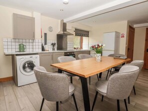 Eine moderne Küche mit integriertem Waschmaschine, einem Holzespeisetisch mit Stühlen und einem kleinen Fenster mit Blick.