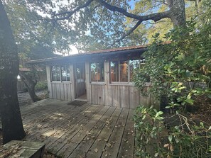 Eine Holzhütte mit einer Terrasse, umgeben von Bäumen.