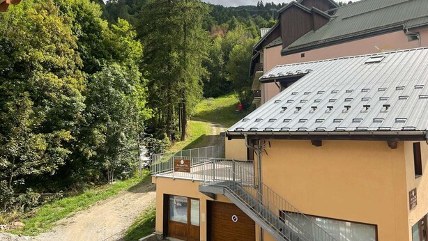 Ein Gebäude mit einem Metall-Dach, einer Holztür und einer Treppe, die zu einem Balkon führt.