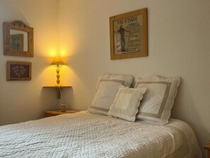 Une chambre à coucher avec un lit, une table de chevet avec une lampe et des tableaux encadrés accrochés au mur.