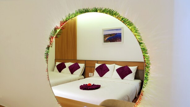 A hotel room with a bed, a nightstand, a mirror, and a picture on the wall. - Anna Seaview Hotel and Spa (Phu Quoc)