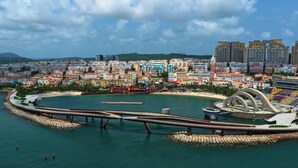 A coastal cityscape with colorful buildings, a waterfront promenade, and a distinctive circular structure. - Anna Seaview Hotel and Spa (Phu Quoc)