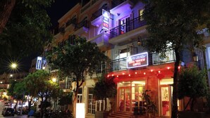 A hotel with a balcony, a sign for a cafe, and a well-lit entrance. - Anna Seaview Hotel and Spa (Phu Quoc)