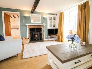 A living room with a fireplace, sofa, TV, and a wooden coffee table. - Ivy Cottage, Winster (Matlock)