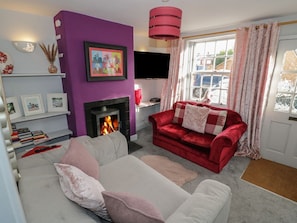 Ein Wohnzimmer mit Kamin, einem roten Sofa, einem grauen Sofa und einem an der Wand befestigten Fernseher.