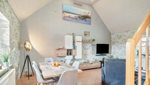 Un interior moderno con una mesa de comedor, sillas, un sofá, un televisor y una estantería.