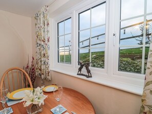 A dining table set with plates, glasses, and a vase of flowers. - Moorcrest in Littleham, Devon. (Bideford)