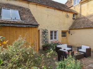 A rustic building with a wooden fence, a small garden, and outdoor furniture. - The Old Dairy, Nettleton (Chippenham)