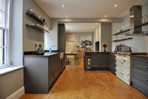 Eine moderne Küche mit grauen Schränken, Holzboden und eingebauten Regalen.