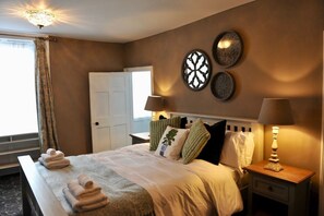 Ein Hotelzimmer mit einem Bett, zwei Nachttischen, einer Lampe, einer Wandleuchte und einer Tür.