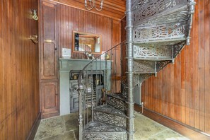 A wooden-paneled room with a metal spiral staircase, a mirror, and a cabinet with a sign. - Southport Coach House, Southport (Southport)