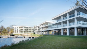 Un edificio moderno de varios pisos con balcones de vidrio y vista al agua.
