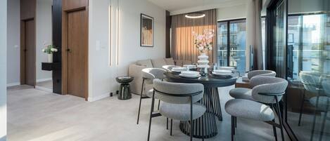 Un comedor moderno con una mesa redonda, sillas tapizadas en gris y un jarrón con flores.
