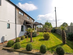 Una propiedad residencial con un césped cuidado, una valla de madera y un cielo despejado.