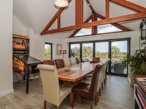 Un comedor con mesa y sillas de madera, un jukebox y grandes ventanales con vistas.