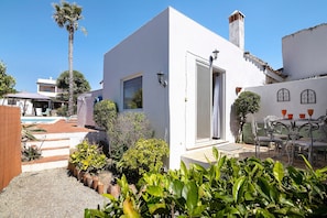 Un edificio blanco con puerta, ventana y un pequeño patio con mesa y sillas.